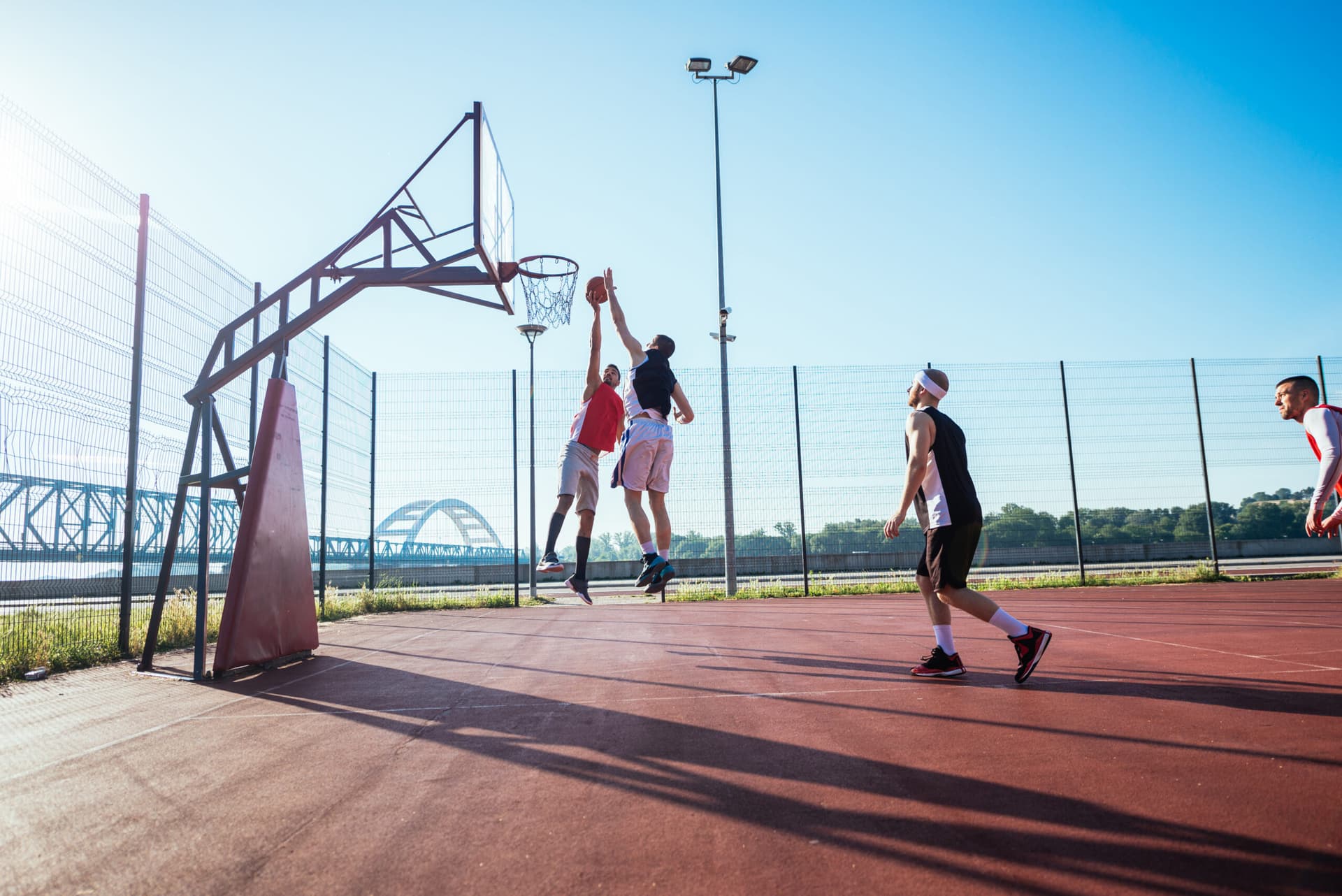 Basketball players jumping on an outdoor court in the sun